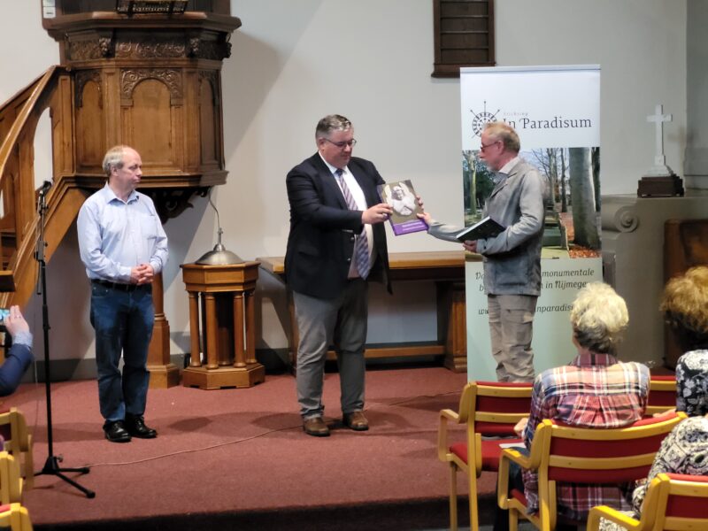 Een foto van het moment dat Wim Desserjer het eerste exemplaar van zijn boek over Begraafplaats Daalseweg overhandigt aan burgemeester Bruls van Nijmegen.